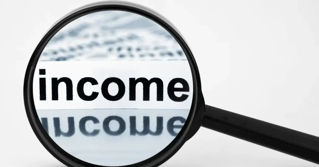 A magnifying glass focuses on the word “income” from a document
